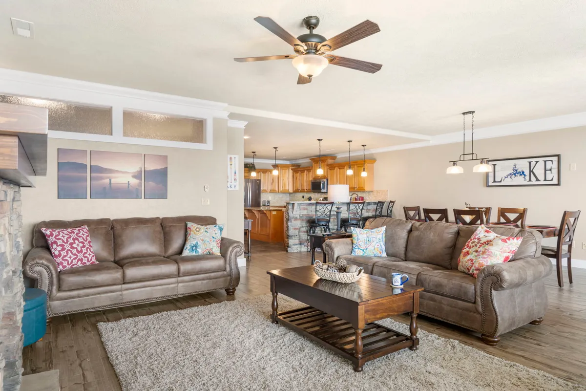 A warm, open-concept space blending the living area, dining area, and kitchen in one cohesive shot. The image shows comfortable sofas, a wooden coffee table, and the dining table, highlighting how the spaces flow together for gatherings and shared moments.