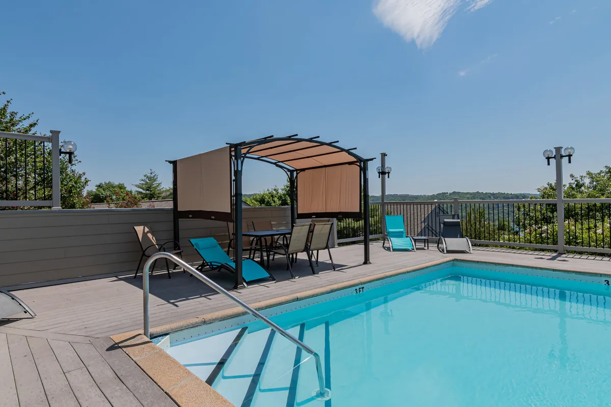 A sparkling resort-style swimming pool is surrounded by lounge chairs, cabanas, and a scenic natural landscape. The space looks inviting for swimming, sunbathing, or gathering with friends and family, enhancing the sense of on-site leisure.