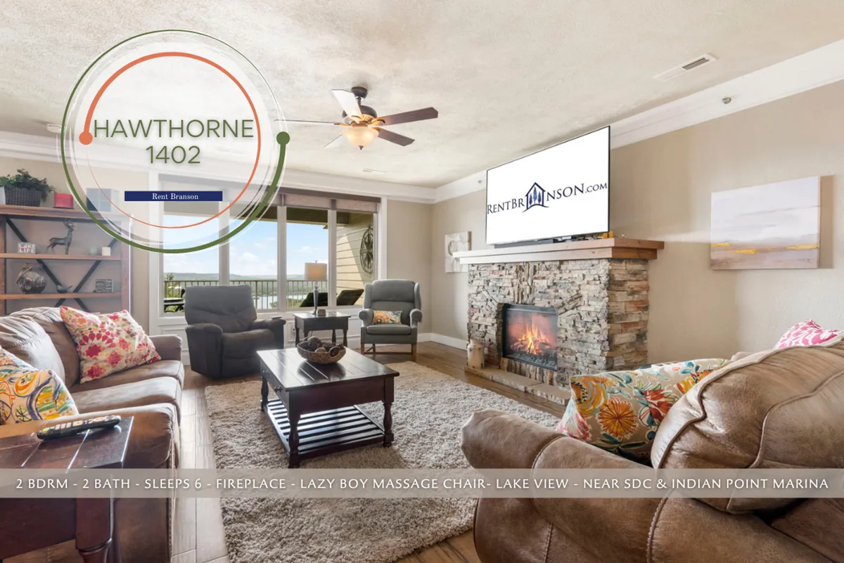 This image features the main living area of the home with a focal fireplace, comfortable seating, and large windows that offer a view of the lake. The layout includes a visible Lazyboy massage chair, sofa, and invites relaxation and togetherness.